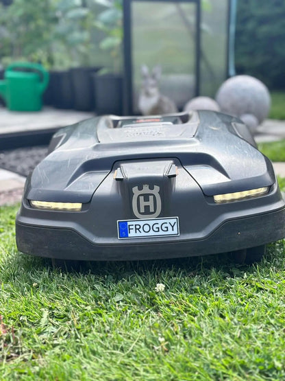 Personlig namnskylt monterad på robotgräsklippare i trädgård